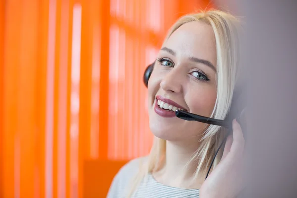 Lachende jonge zakenvrouw, het dragen van een headset beantwoorden, oproepen een — Stockfoto