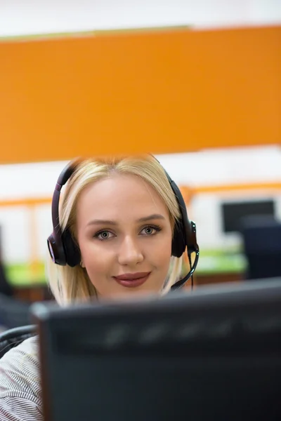 Atraktivní mladá žena v šatech sedí v kanceláři centra volání a — Stock fotografie