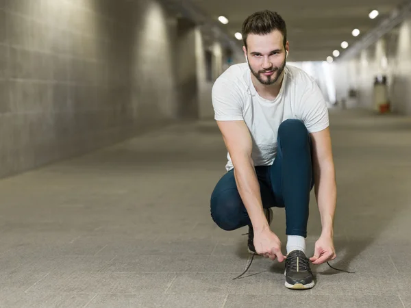 Urban jogger atando sus zapatillas en un gran puente . — Foto de Stock