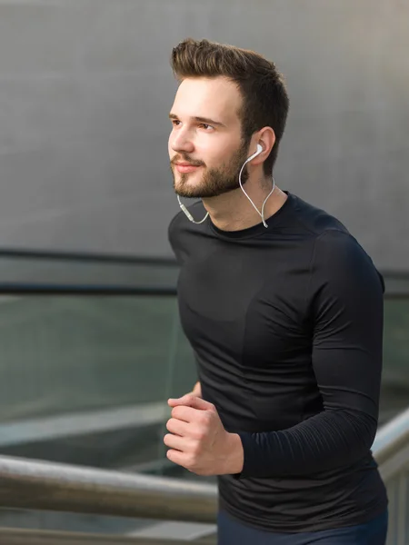 Portrait of male runner jogging fast down the bridge with copy s — Stock Photo, Image