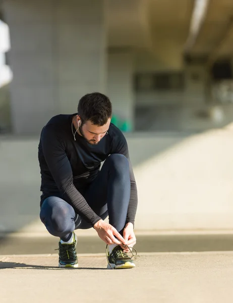 Urban jogger atando sus zapatillas en un gran puente . — Foto de Stock
