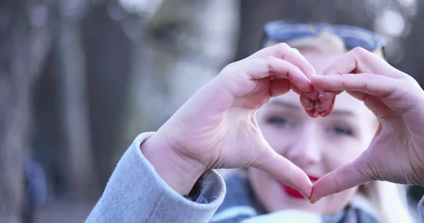 Mooie Kaukasische blonde vrouw toont hart teken met vinger — Stockfoto