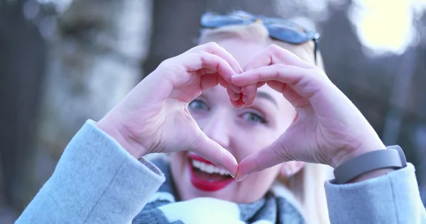 Beautiful caucasian blonde woman  showing heart sign with finger — Stock Photo, Image