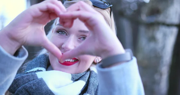 Mooie Kaukasische blonde vrouw toont hart teken met vinger — Stockfoto