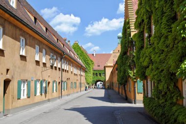 Augsburg, Almanya: Hardal kaplama duvarlar, sarmaşık kaplı binalar ve dünyanın en eski sosyal konut kompleksi Fuggerei 'de hâlâ kullanımda olan temiz sokaklar. Duvarlarla çevrili bir bölge.. 