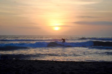 Gün batımında sörfçü. Legian Sahili, Pantai Lejyonu, Bali, Endonezya. Bali birçok sörf okulu olan popüler bir sörf mekanıdır. Kuta ve Seminyak yakınlarında. 