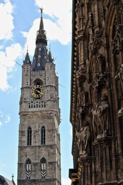 Het Belfort van Gent - Gent 'in çan kulesi, arka plandaki eski şehir merkezine ve sağdaki Stadhuis Gent Belediyesine bakan üç ortaçağ kulesinden biridir.. 
