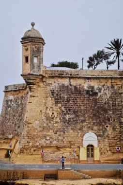 Senglea, Malta 'daki Gardjola Bahçeleri istilacılara karşı uyarıda bulunmak için inşa edilmiş, kule pervazları, gözetleme kuleleri, Il-gardjola onların ihtiyatlı olduklarını sembolize eden bir göz ve kulakla oyulmuştur..