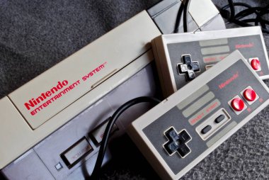 Nintendo Entertainment System (NES), Nintendo tarafından üretilen 8-bit üçüncü nesil ev oyunu konsolu. NES Denetim Güvertesi ev oyun konsolu denetleyiciler ile.