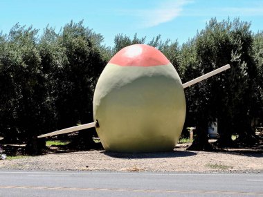 A 15-foot-tall green olive skewered by a similarly supersized red toothpick. Sits at the edge of an olive grove in honor of Corning, the Olive City. Roadside attraction in California's central valley.