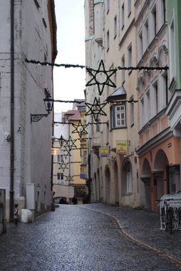 Regensburg, Germany: Krautermarkt Street is decorated for Christmas with garlands, stars and lights. Wet cobblestones and empty alleys. No people. Photo has a grainy texture to add mood. 