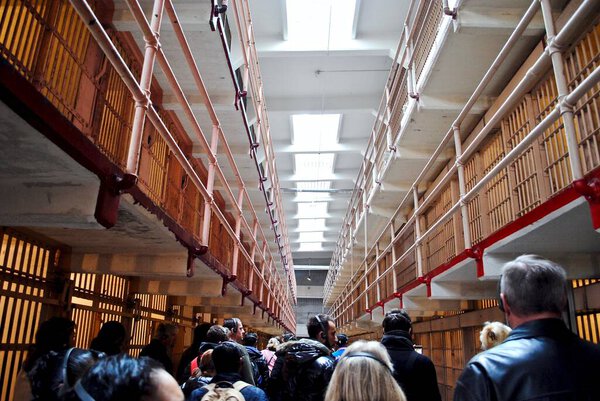 San Francisco, California: Visitors wearing headsets at Alcatraz Federal Penitentiary Prison. Prison corridors were named after major U.S. streets such as Broadway and Michigan Avenue.