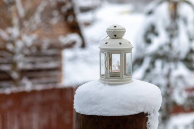 Kasabanın dışında karla kaplı bir direğin üzerinde mum olan bir lamba.. 