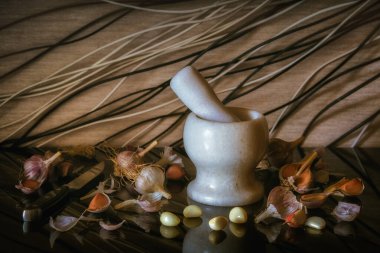 Sarımsak ve tokmaklı beyaz bir taş havan. Yemek ve alternatif tıp malzemeleri. Sağlık ve lezzet kalitesi. Pencereden gelen ışık.