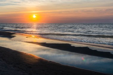 Baltık Denizi üzerinde gün batımı. Kumsal. Güneş ışınları suya yansıyor..