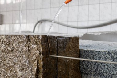 Taş testeresi. Granit taşları kesmek için bir makine. Taş ustasının atölyesinde granit kesmek. Tek telli testereler