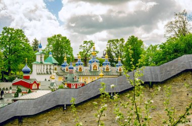 Pskov-Pechora Manastırı Duvarı. Duvarın arkasında çan kubbesi ve tapınağın kubbeleri var..