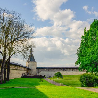 Kremlin duvarı boyunca ağaçlar ve çimenler dikilmiş bir patika var. Gökyüzünde ağır bulutlar süzülüyor.