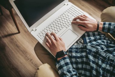 Evde dizüstü bilgisayar kullanan yakışıklı bir genç. Öğrenciler odasında dinleniyor. Çevrimiçi alışveriş, ev işi, serbest çalışma, çevrimiçi öğrenme, öğrenim kavramı. Uzaklık eğitimi