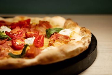 Siyah tahta üzerinde domates sebzeli pizza. Restoranda ikiye bölünmüş.