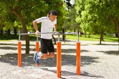 Parkta barfiks çeken siyah bir adam vardı. Rastaları vardı ve siyah-beyaz giyinmişti.