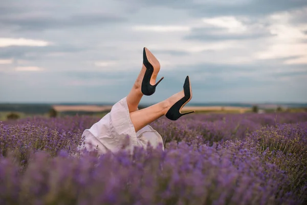 選択的フォーカス 女の子の足はラベンダーの茂みから突き出ています ラベンダー紫色の花の茂み ラベンダー畑の芳香のある花 ロイヤリティフリーのストック画像