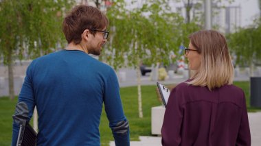 Sokakta birlikte yürüyüp konuşan iki profesyonel iş arkadaşının, gündelik giyinmiş genç bir adamın ve bir kadının geçmişine bakın. Düşüncelerini anlatırken hareket ediyorlar. Olumlu konuşma.