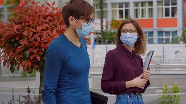 İş gençliği başarılı insanlar konsepti. Maske takan erkek ve kadın aşağı inip iş konuşuyorlar, mutlu yüzler. Laptop Panosu. Salgın dönemindeki insanlar.