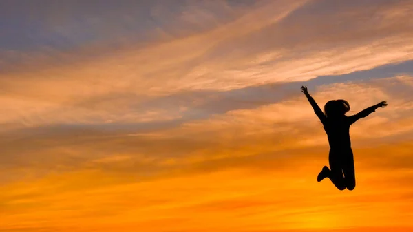 日没時に女性をジャンプ シルエット 自由と幸福 ロイヤリティフリーのストック写真