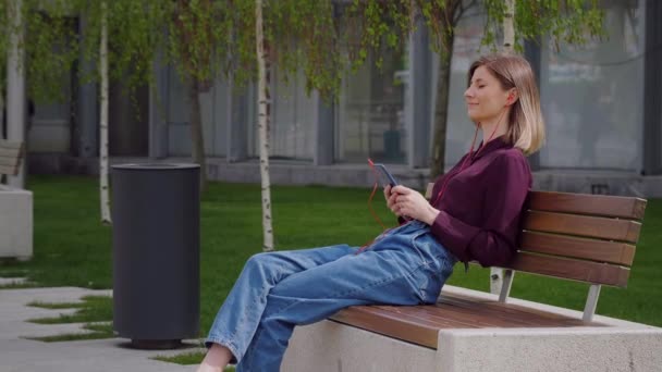 Mulher Sentada Banco Usando Fones Ouvido Para Ouvir Música Escolhendo — Vídeo de Stock