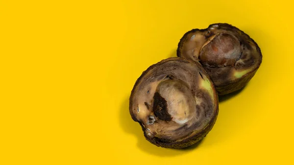 Çürümüş avokado yenmez. Sarı arka planda olgunlaşmış avokado meyvesi ikiye bölünmüş. Yemek israfını bırak. Boşluğu kopyala.