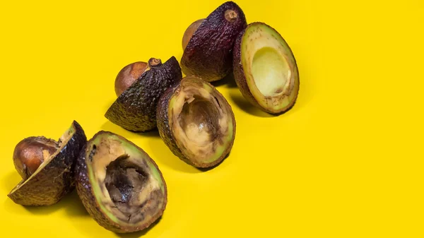 Sarı arka planda üç Kötü Avokado. Yaratıcı kompozisyon çürümüş Unhelthy Avokado Kavramı. Olgunlaşmış avokado meyvesi ilk başta sarı masa arkaplanından ikiye bölünmüş. Boşluğu kopyala.
