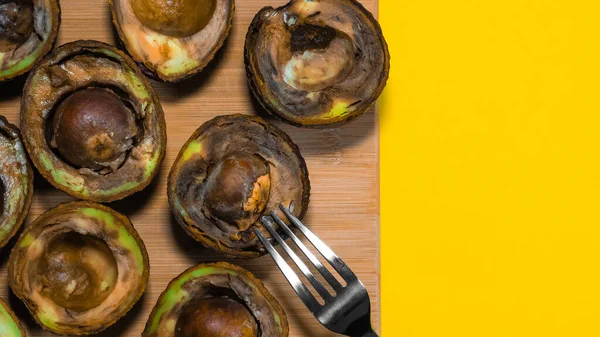 Kirlenmiş tropikal meyveler. Sarı arka planda Kötü Avokado Yarı Yakın. Kötü vejetaryen yemeği. Çürük Avokado odun öğütücüsünde. Uzayı kopyalayın Necomestibile Food. Yemek israfını bırak. Olgunlaşmamış Meyve Konsepti.