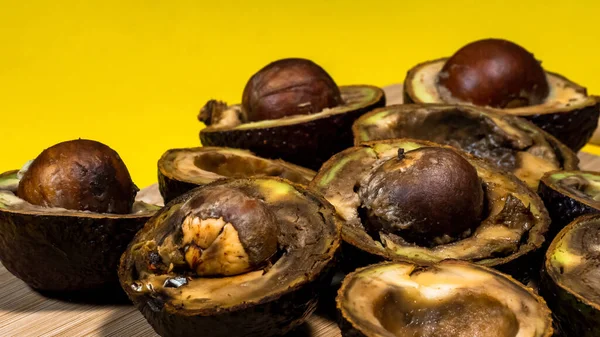Kirlenmiş tropikal meyveler. Sarı arka planda Kötü Avokado Yarı Yakın. Kötü vejetaryen yemeği. Çürük Avokado odun öğütücüsünde. Uzayı kopyalayın Necomestibile Food. Yemek israfını bırak. Olgunlaşmamış Meyve Konsepti.