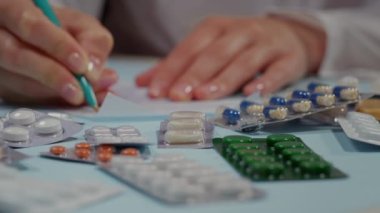 Kapatın, haplar masada, doktor reçete yazıyor. İlaveler alınıyor