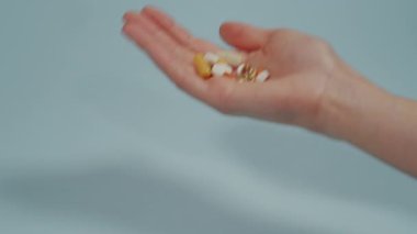 Avucunun içinde çeşitli şekil ve renklerden oluşan tablet ve kapsüller var. Ağrı kesici, antibiyotik hapı, kas kurutma hapı.