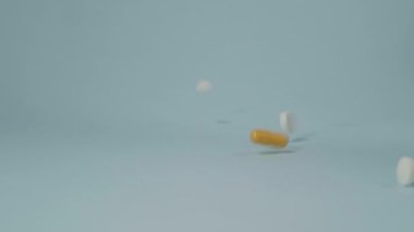 Mavi masaya çeşitli şekil ve renklerden haplar, tabletler ve kapsüller döküldü. Yavaş çekim