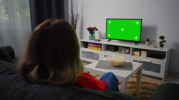 Girl Watch Green Chroma Key Screen TV,リラックスしたソファの家に座って.リビングルームの女性スポーツマッチを見て,ニュース,ホームコメディテレビ番組や緑の画面上の映画. — ストック動画