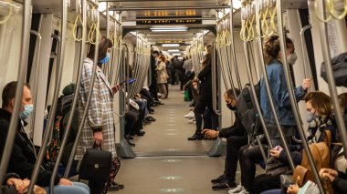 BuCHAREST, ROMANIA - 15 Mayıs 2021: Coronavirus krizi sırasında metro. 2021 ilkbaharında trende maske takan insanlar metroda ellerinde telefonlar olan insanlar. Metro treni toplu taşıma.