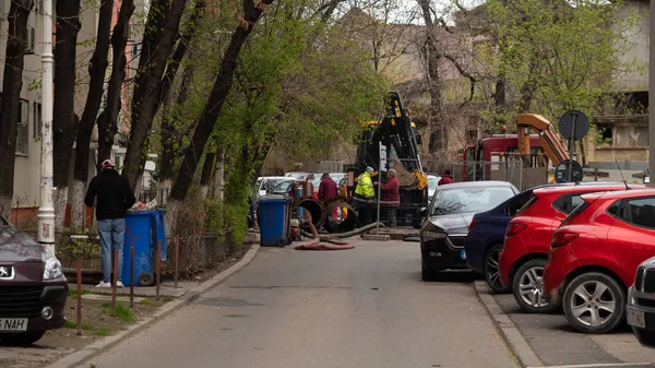 İşçiler şehir kanalizasyonunda tamirat yapıyorlar. Traktör, şehirde onarım, asfaltta delik..
