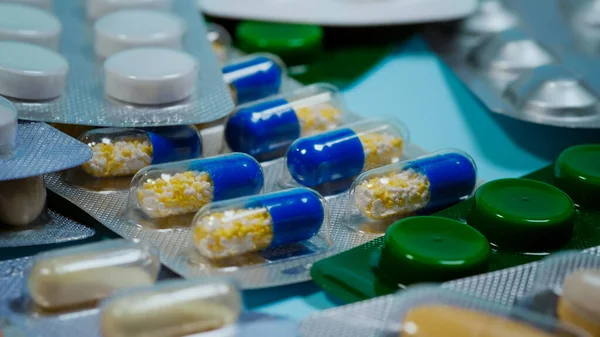 Mavi arka planda çeşitli şekil ve renklerde kabarcık, hap, tablet ve kapsüller