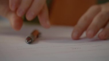 İki el, masa üzerinde kağıt kağıtlarla kaplı bir kontrat imzalar. Konforlu bir ofis ortamında uzaktan çalışmanın odak ve adanmışlığını gözler önüne serer..