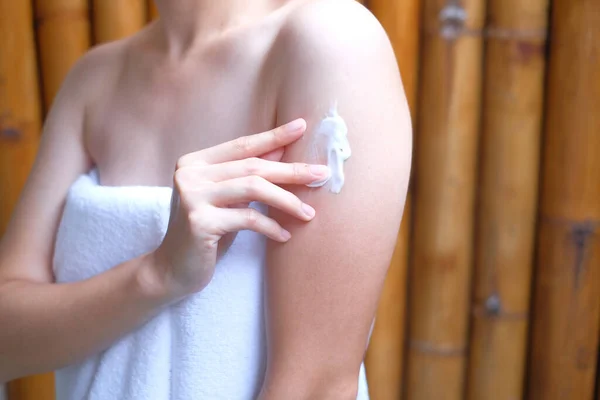 Woman applying cream,lotion on arm with wood background, Beauty concept.