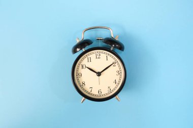 Black vinatge alarm clock with blue background.