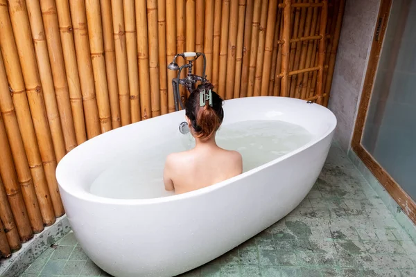 Lüks banyo Asya kadın sağlık spa 'sı otel süitinin sıcak su küvetinde dinleniyor. arka plan.