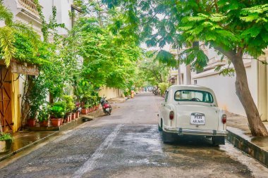 Puducherry, Hindistan - 9 Aralık 2013. Eski Fransız sömürge kasabasının Beyaz Kasaba bölgesinde, Pondicherry olarak bilinen bir caddeye bej renkli bir eski Büyükelçi arabası park edilmiştir..