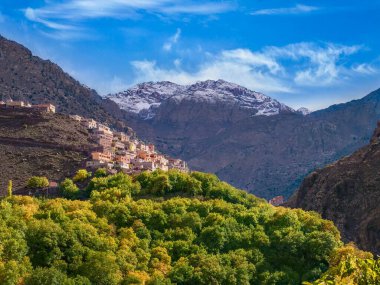 Fas 'ın Yüksek Atlas Dağları' nda, arka planda Kuzey Afrika 'nın en yüksek dağı olan kar kaplı Jbel Toubkal' ın bulunduğu dik bir yamaçta bir Berber köyü bulunmaktadır..