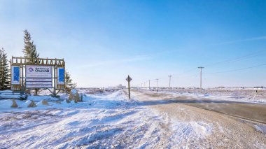Tundra 'da dondurucu soğuğun altında, kuzeydeki Churchill, Manitoba, Kanada yakınlarındaki bir turist hoş geldin tabelasının yanında karayolu boyunca kar eserken,.