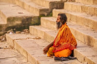 Varanasi, Hindistan - 14 Kasım 2015. Hintli bir sadhu, şafak vakti antik Varanasi şehrinin halk ghatlarında meditasyonda bağdaş kurarak oturur..