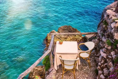 İtalya 'daki Amalfi Sahili' nin sığ mavi sularının yanındaki tenha bir sahil kenarında iki kişilik güzel bir masa..